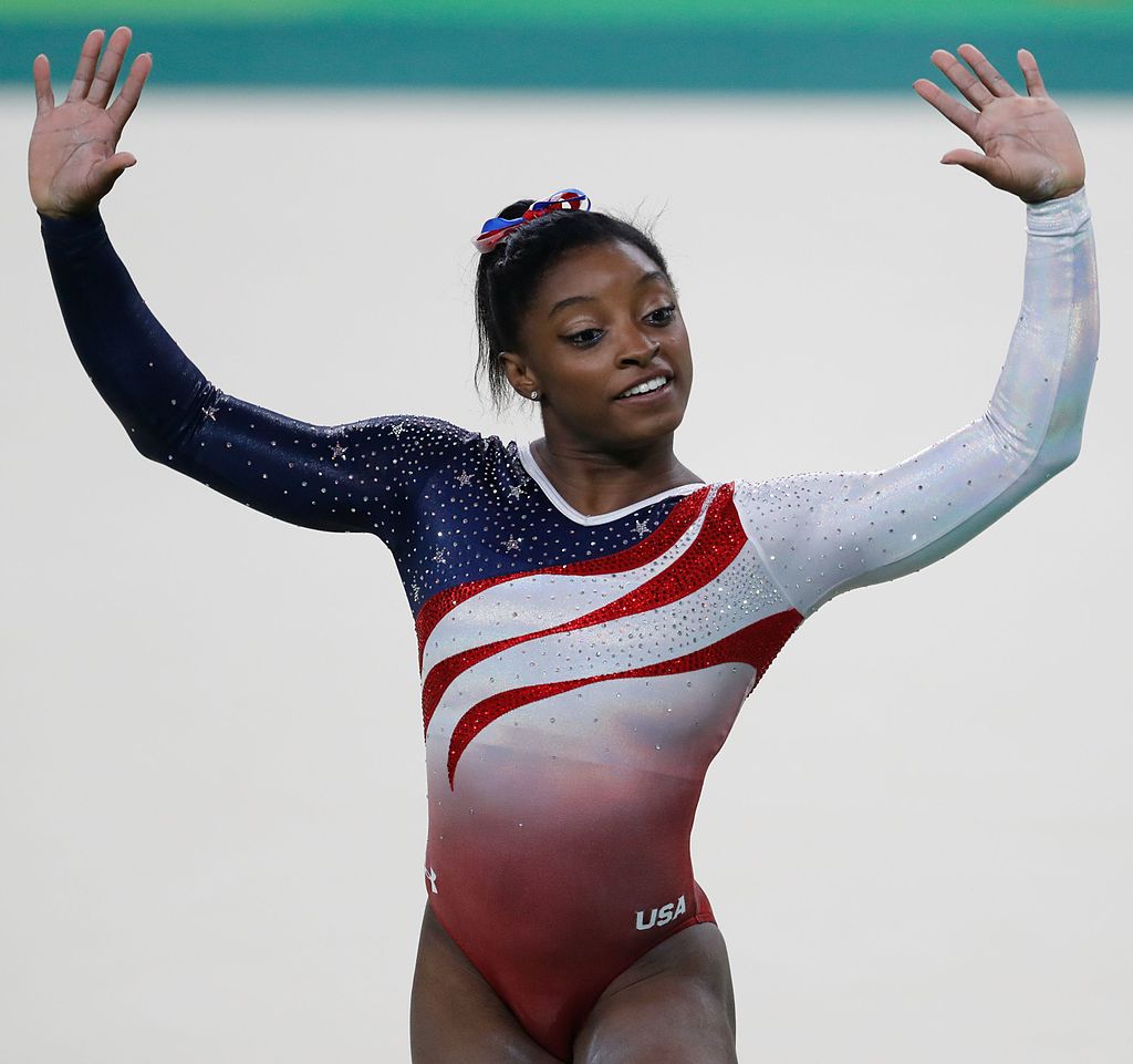 "Simone Biles smiling and waving at the 2016 Rio Olympics.'"